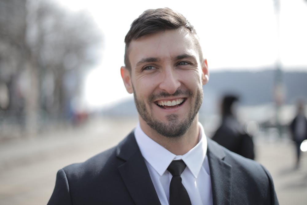 Homem sorridente usando terno preto. Ilustração do texto sobre câncer de próstata.