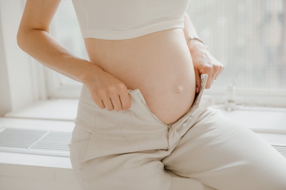 Gestante usando calça branca. Ilustração do texto sobre pilates para gestantes.